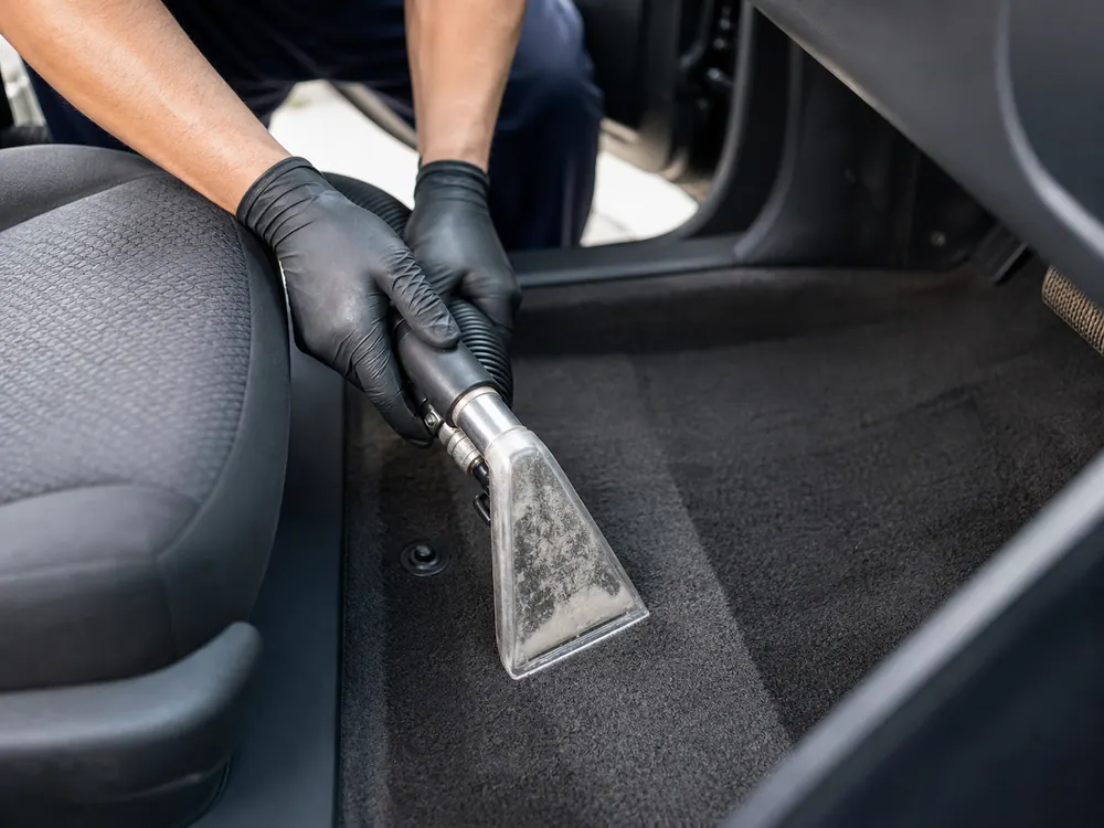 Extractor cleaning a car seat and carpet area.